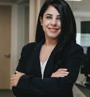 A woman in black jacket standing with her arms crossed.